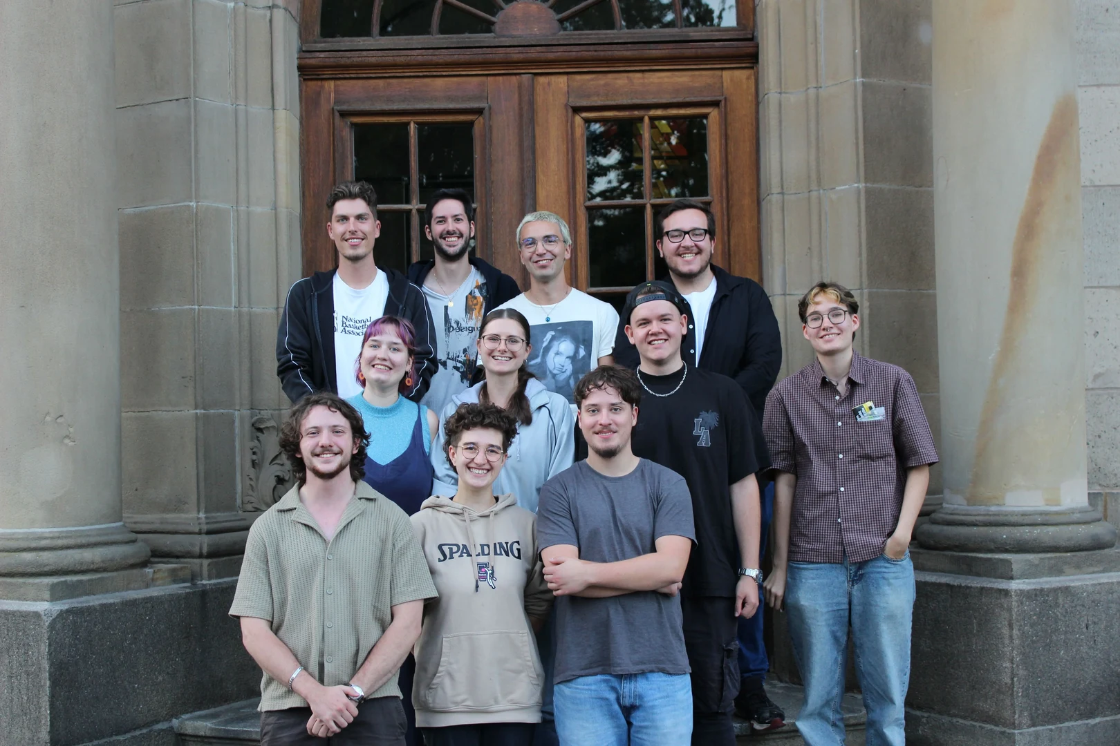 Eine Wissenschaftlerin und ein Wissenschaftler arbeiten hinter einer Glasfassade und mischen Chemikalien mit Großgeräten.