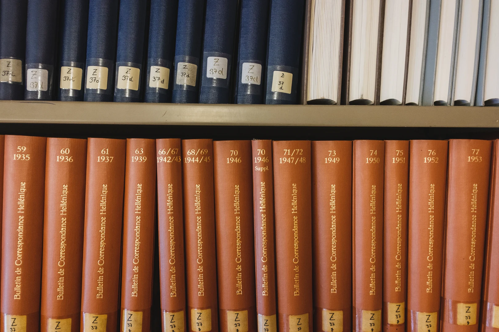 Eine Wissenschaftlerin und ein Wissenschaftler arbeiten hinter einer Glasfassade und mischen Chemikalien mit Großgeräten.