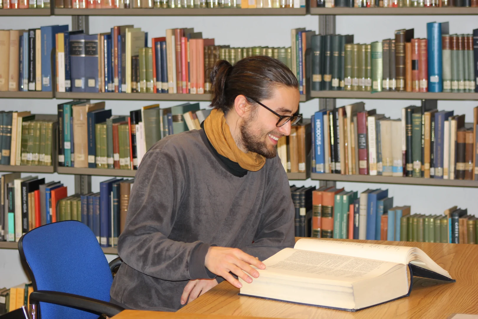 Eine Wissenschaftlerin und ein Wissenschaftler arbeiten hinter einer Glasfassade und mischen Chemikalien mit Großgeräten.