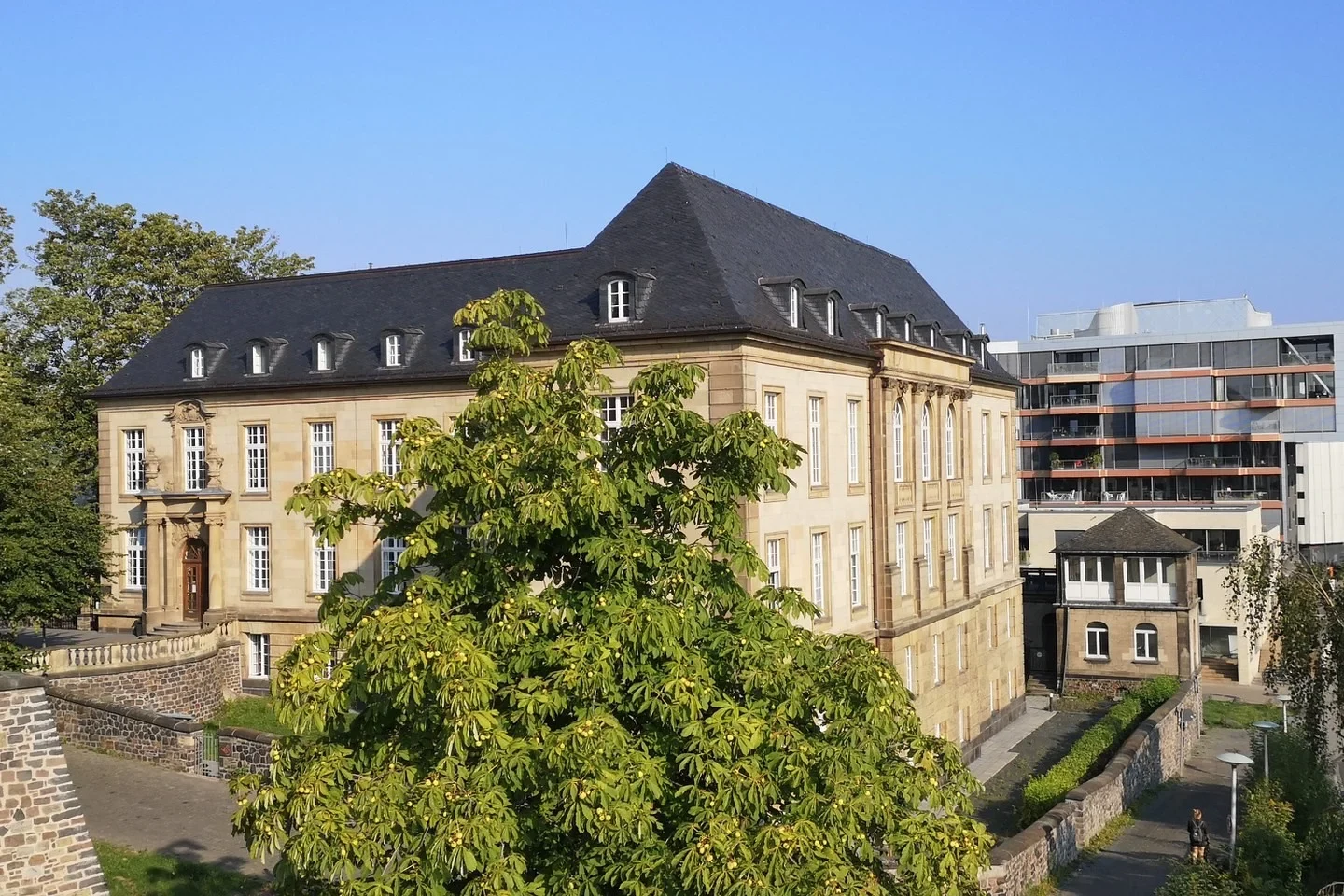 Eine Wissenschaftlerin und ein Wissenschaftler arbeiten hinter einer Glasfassade und mischen Chemikalien mit Großgeräten.