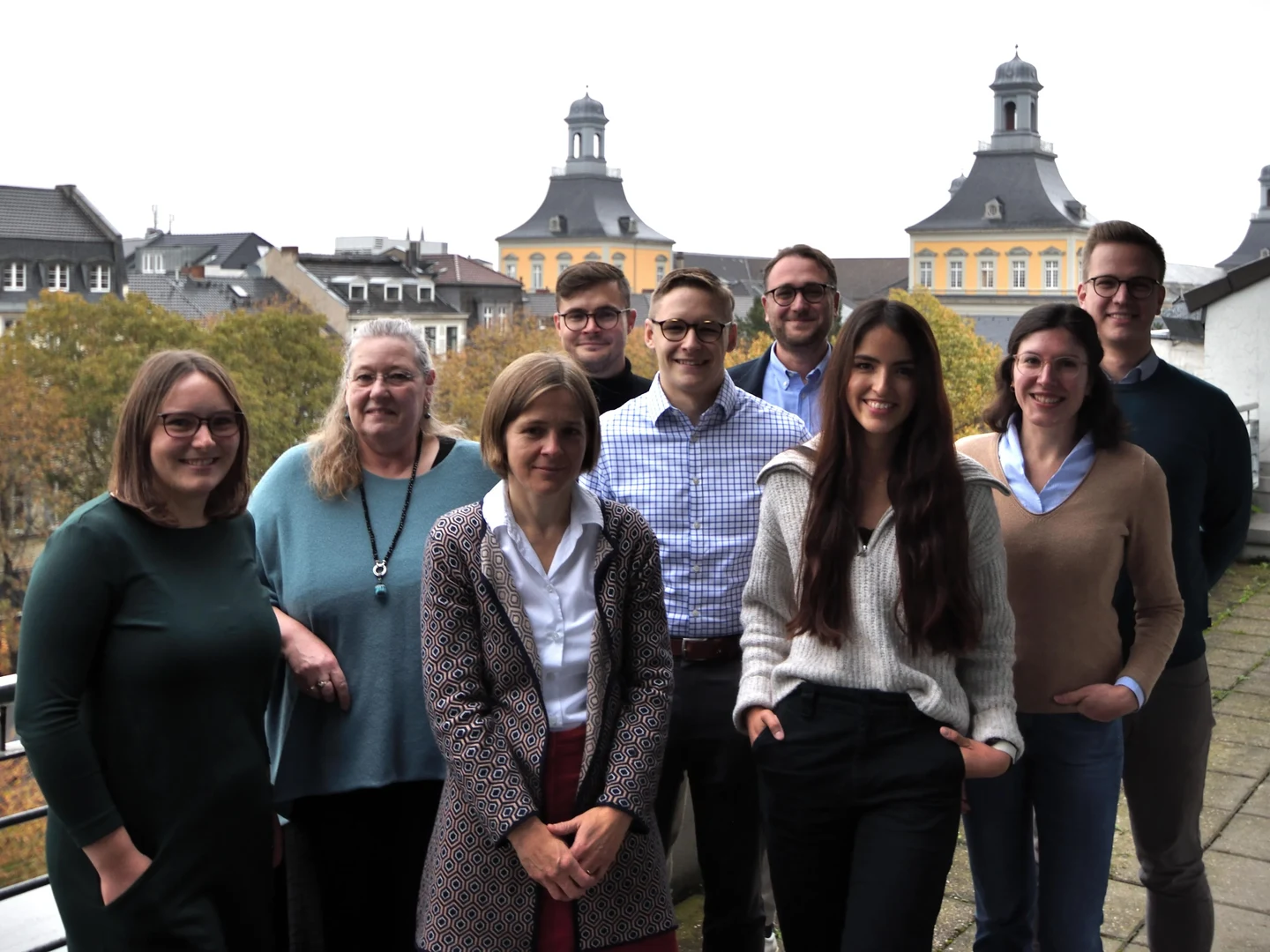 Eine Wissenschaftlerin und ein Wissenschaftler arbeiten hinter einer Glasfassade und mischen Chemikalien mit Großgeräten.