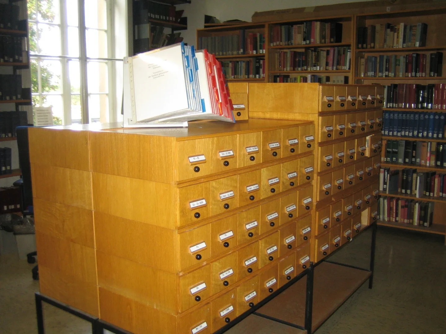 Eine Wissenschaftlerin und ein Wissenschaftler arbeiten hinter einer Glasfassade und mischen Chemikalien mit Großgeräten.